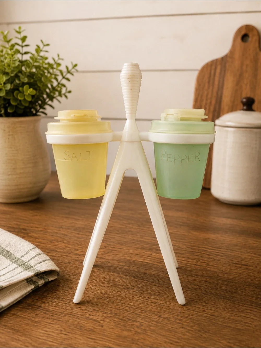 Vintage Tupperware salt and pepper shakers with white atomic-style tripod caddy.